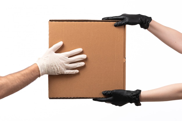 Коробка доставки вид спереди доставляется от женщины к мужчине в перчатках на белом