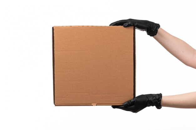 A front view delivery box hold by female hand in black gloves on white desk