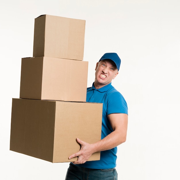 Front view of delivery man holding heavy cardboard boxes in hands