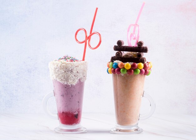 Front view of dessert glasses with straws and colorful candy