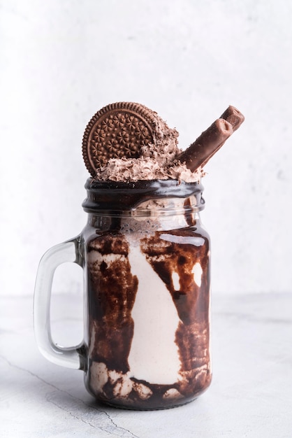 Front view of dessert in jar with chocolate biscuits and rolls