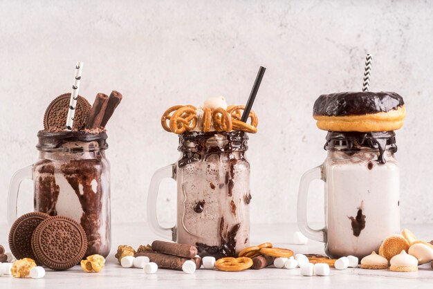 Front view of desserts in jars with biscuits and donuts