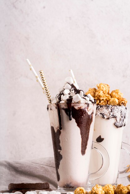 Front view of desserts in jars with marshmallows and popcorn