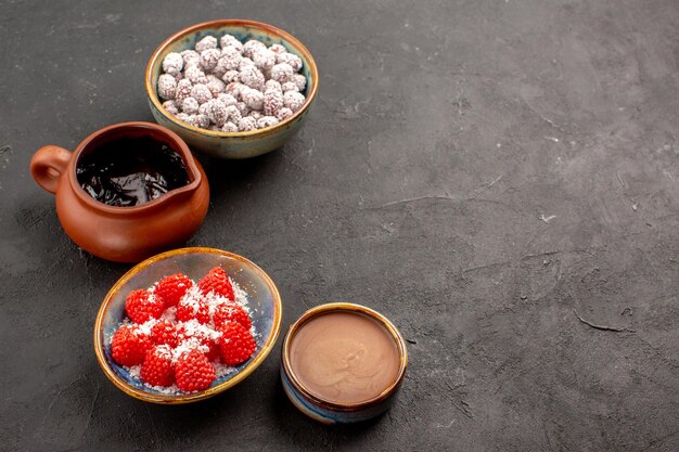 Front view different candies with chocolate syrup on dark grey background color candy tea biscuit