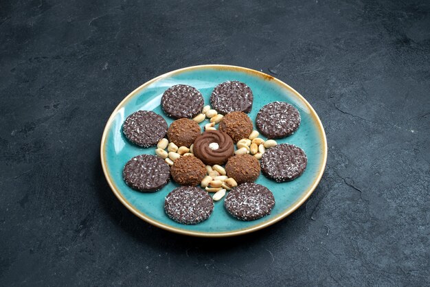 Вид спереди различных шоколадных печений с орехами на темно-серой поверхности