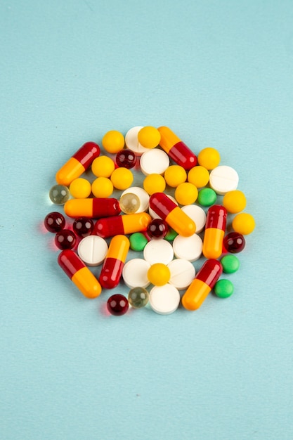 вид спереди разноцветные таблетки на синей поверхности вирус лаборатории здоровье covid- больница наука пандемия наркотиков цвета