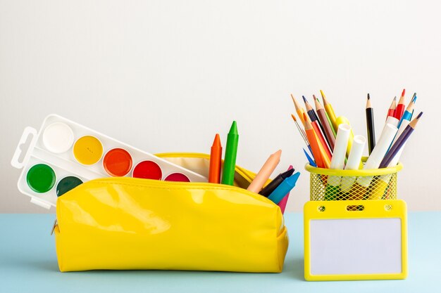 파란색 책상에 카피 북이있는 노란색 펜 상자 안에 전면보기 다른 다채로운 연필