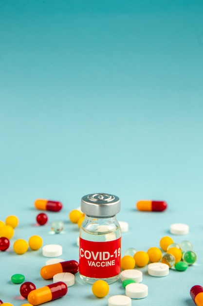 front view different colorful pills with vaccine on blue surface lab color health covid- hospital science pandemic drug