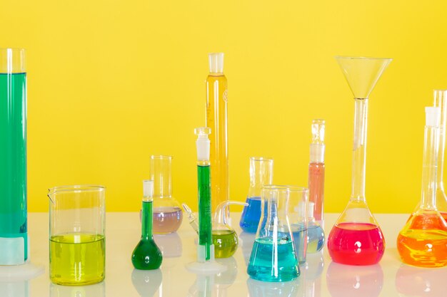 Front view of different colorful solutions inside flasks on the table