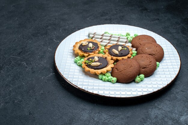 Front view different cookies chocolate based with sweet sugar candies on grey surface