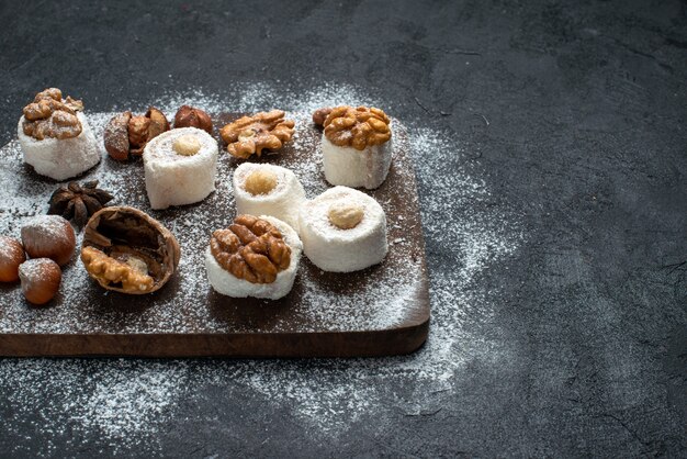 Front view different cookies with cakes and walnuts on the dark-grey surface cake biscuit sugar bake sweet cookie