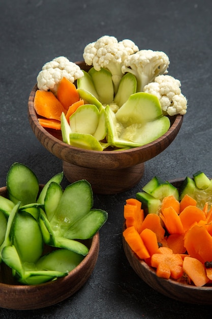 ダークグレーのスペースにある鉢の中のさまざまなデザインの野菜の正面図