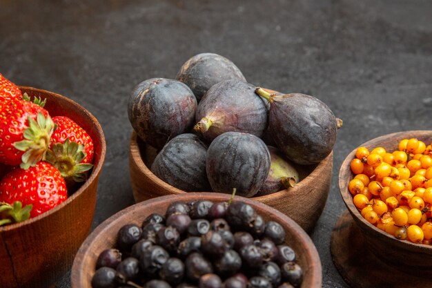 Вид спереди разные свежие фрукты внутри тарелок на темном фоне цветная фотография фруктов много спелых соков