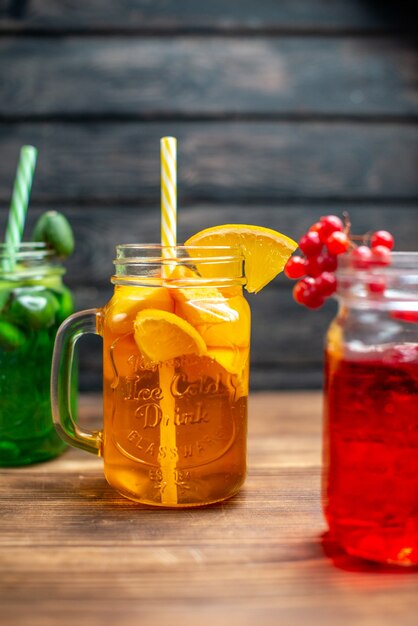 Front view different fresh juices inside cans on brown wooden desk