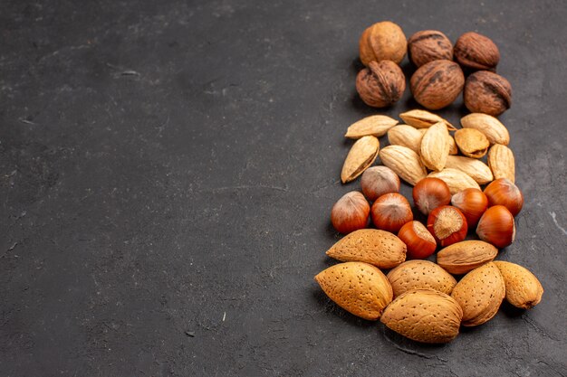 Front view of different fresh nuts on dark surface