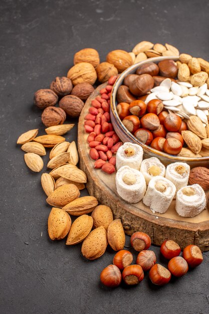 Front view of different fresh nuts with confitures on dark surface