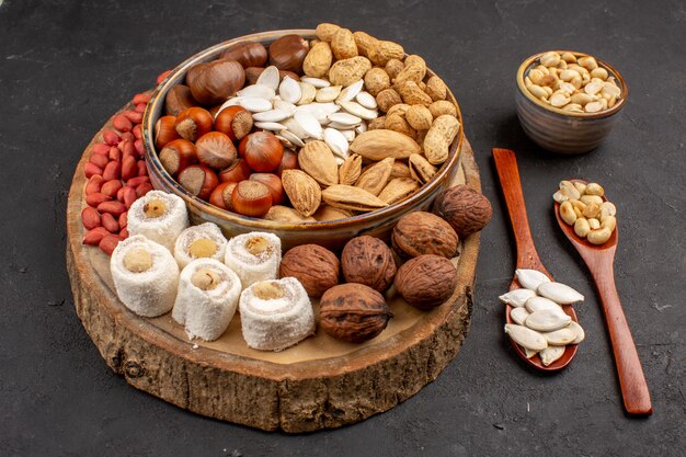 Front view of different fresh nuts with confitures on dark surface