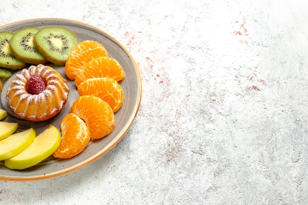 Front view different fruits composition fresh and sliced fruits with little cake on the white background mellow ripe fruits health