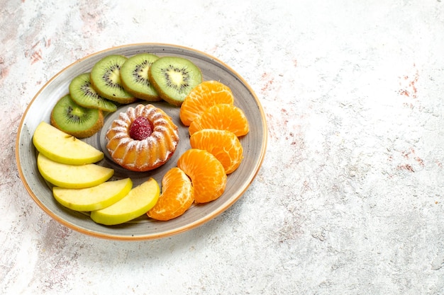 正面図さまざまな果物の組成新鮮なスライスされた果物と白い背景の上の小さなケーキまろやかな熟した果物の健康