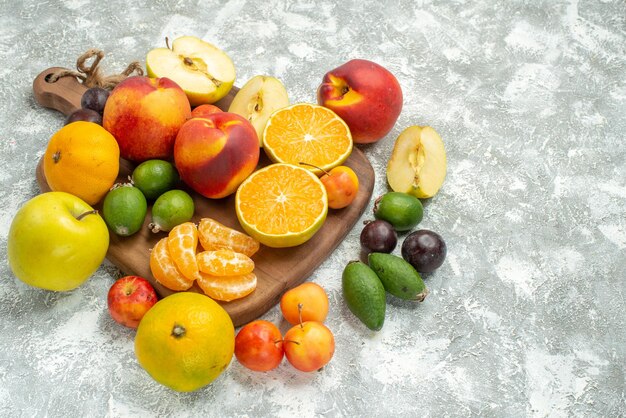 Front view different fruits composition sliced and whole fresh fruits on a white space