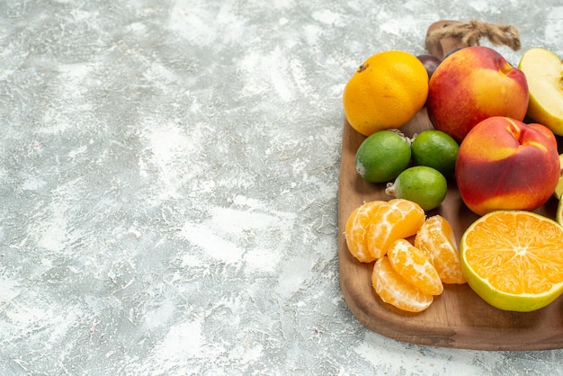 Vista frontale composizione di frutta diversa affettata e frutta fresca intera su spazio bianco