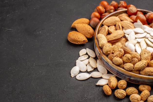 Front view of different nuts fresh nuts inside tray on dark surface