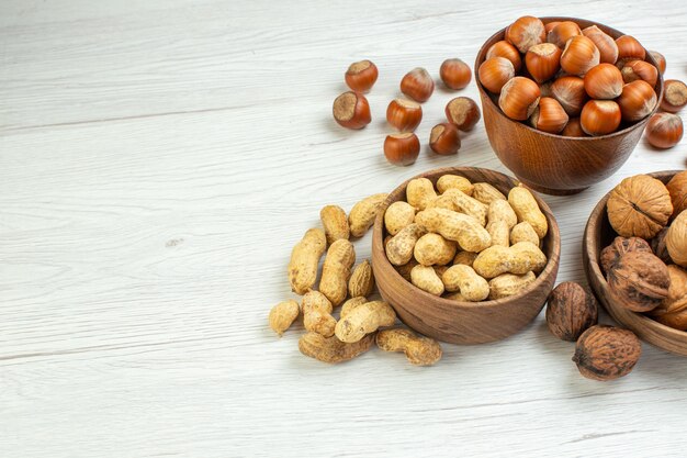 Вид спереди разные орехи, арахис, фундук и грецкие орехи на белой поверхности