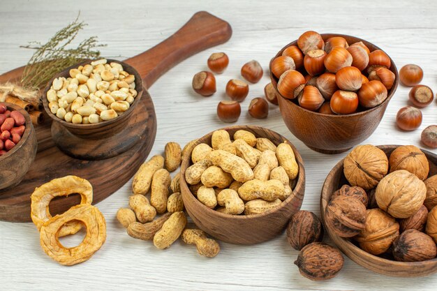 Вид спереди разные орехи, арахис, фундук и грецкие орехи на белой поверхности