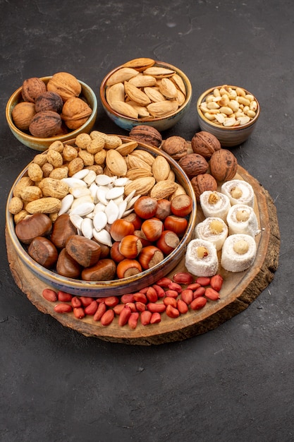 Front view of different nuts with white confitures on a grey surface