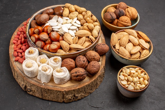 Front view of different nuts with white confitures on the grey surface