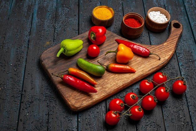 Front view different peppers with seasonings on dark desk