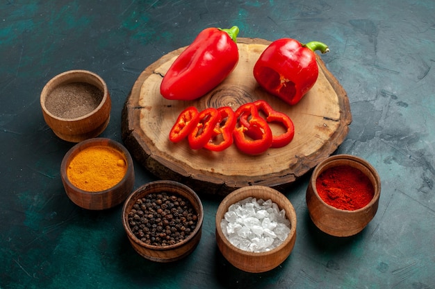 Front view different seasonings with red bell-pepper on dark surface