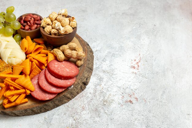 Front view different snacks nuts cips cheese and sausages on white floor nut snack meal food