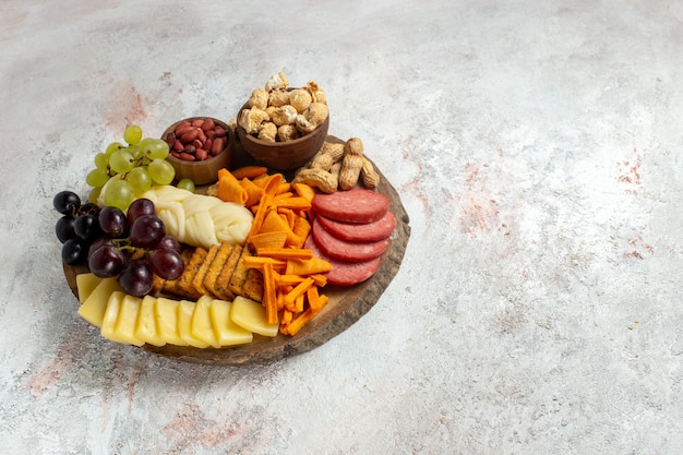 Вид спереди разные закуски, орехи, чипсы, виноград, сыр и колбасы на белом фоне, ореховая закуска, еда, фрукты