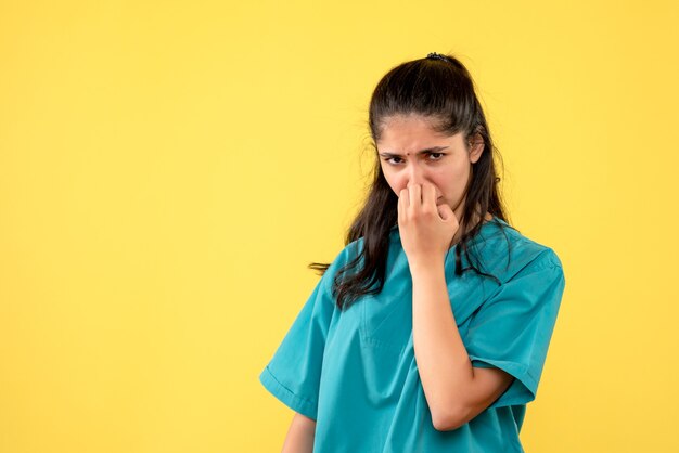 Front view disappointed woman doctor in uniform standing on yellow background copy place