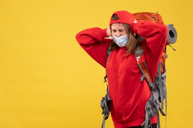 Front view displeased female tourist with backpack and mask holding ears