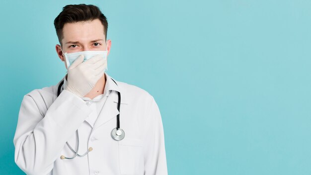 Вид спереди доктора, охватывающий рот во время ношения медицинской маски