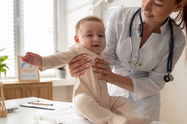 Foto gratuita bambino della holding del medico di vista frontale