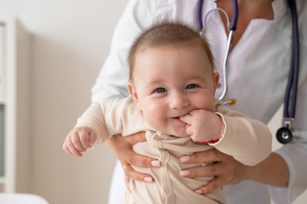 Foto gratuita bambino della holding del medico di vista frontale