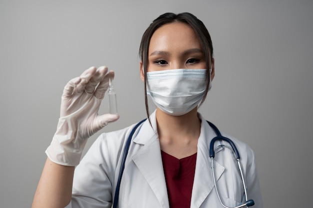 Free photo front view doctor with mask holding vial