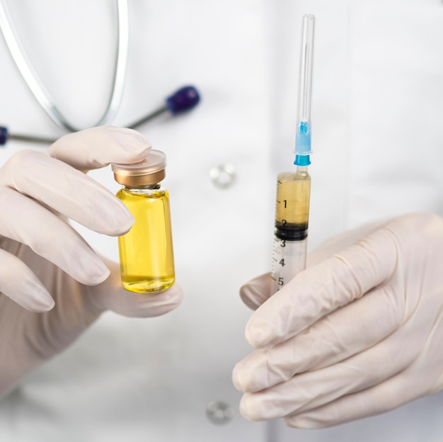 Free photo front view of doctor with surgical gloves holding vaccine and syringe