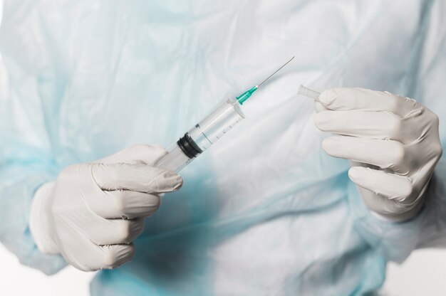Front view of doctor with syringe and surgical gloves