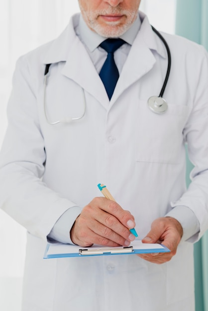 Front view of doctor writing on clipboard