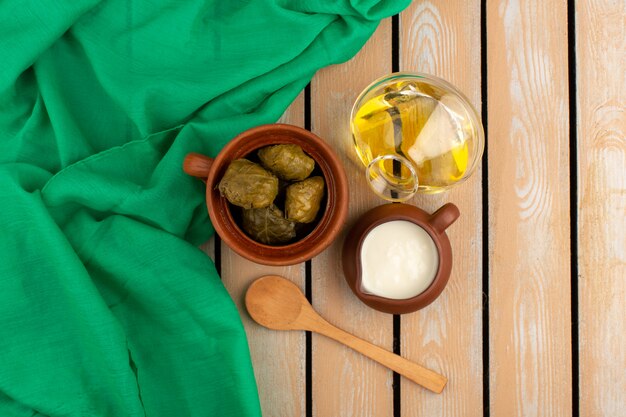 front view dolma famous eastern meal with minced meat inside along with yogurt and olive oil on the brown floor