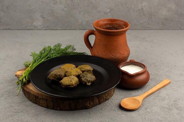 front view dolma famous eastern meal with minced meat inside black plate on the brown desk and grey floor