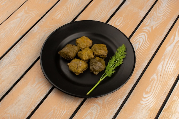 Free photo front view dolma tasty meat meal inside black plate on the rustic wooden floor