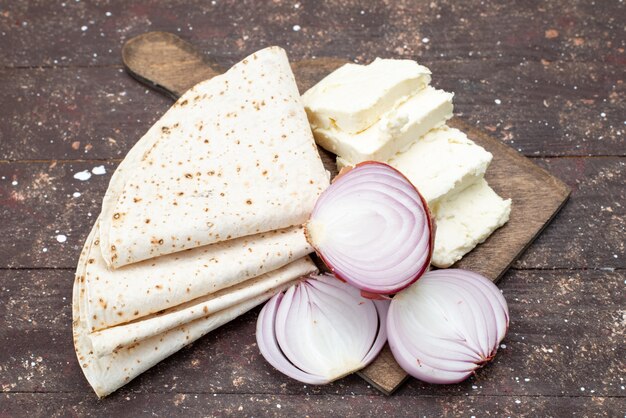 Front view of dough lavash with onions and white cheese on the brown wooden surface