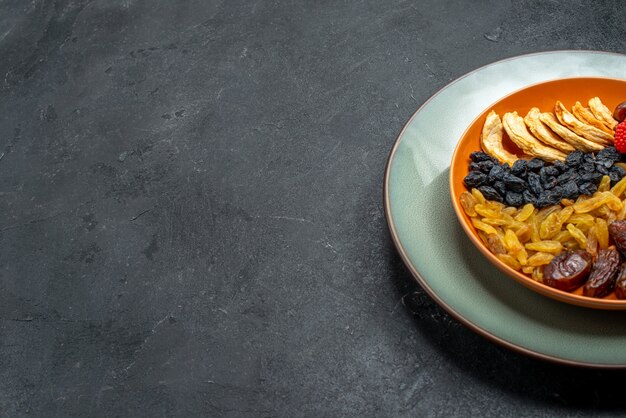 Front view dried fruits with raisins inside plate on the grey space