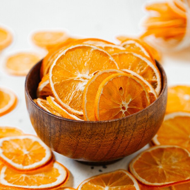 Вид спереди сушеные апельсиновые кольца, сладости внутри и снаружи, маленькая тарелка на белом столе, фруктовый сухой изюм