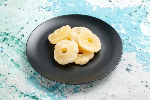 Front view dried pineapple rings inside plate on blue surface